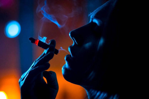 dívka u okna kouření cigaret v noční světlo, silueta. - Fotografie, Obrázek