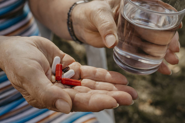пожилая женщина рука с таблетками и стаканом воды
 - Фото, изображение