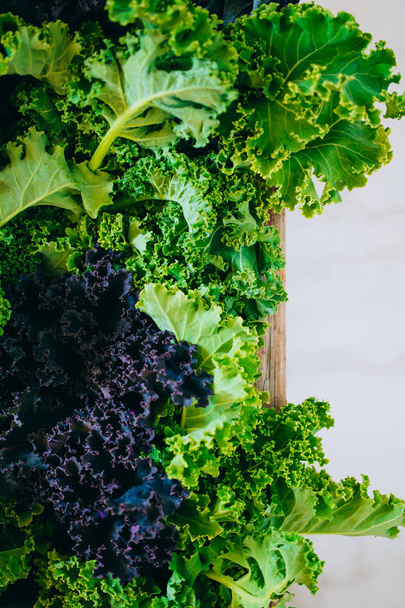 Fresh green and purple kale in a wooden box on a marble background - Foto, immagini