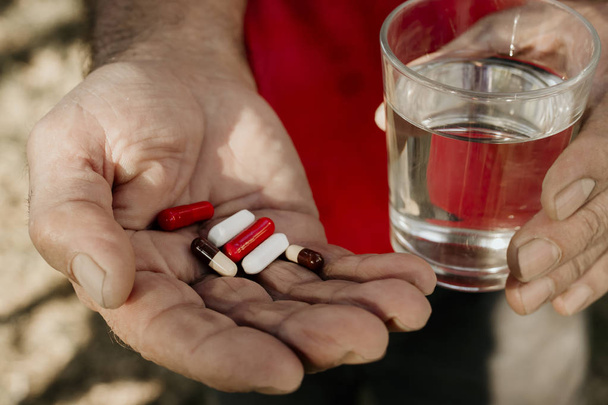 старший рука с таблетками или лекарствами и стаканом воды
 - Фото, изображение