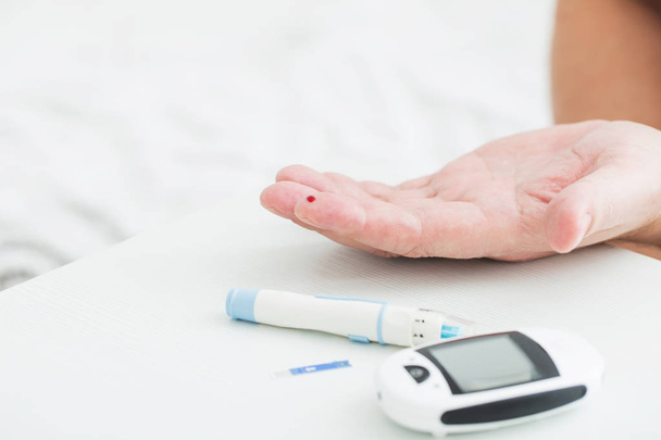 medicine, diabetes, glycemia, health care and people concept - close up of male finger with test stripe - 写真・画像