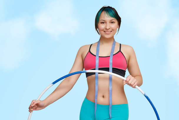 beautiful young sporty girl with a Hoop and a measuring tape on the background of blue sky - Foto, Imagen