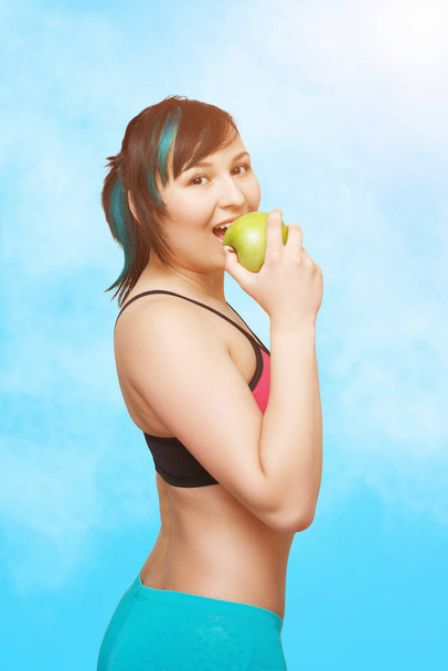 young beautiful girl eating an Apple. on a blue sky background - Photo, image