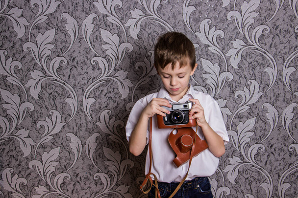 ein Junge im weißen Hemd hält eine alte Kamera - Foto, Bild