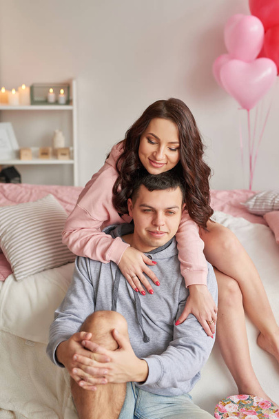 giovane coppia innamorata a casa festeggia San Valentino il 14 febbraio, un bouquet di rose rosse e palloncini a forma di cuore decorare la stanza
 - Foto, immagini