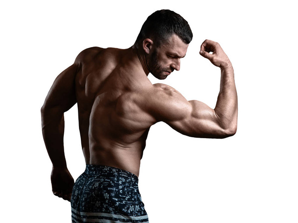 isolated brutal athletic man with a muscular body poses, showing off his biceps. The concept of a healthy lifestyle - Photo, Image