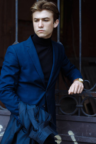 Portret van een jonge, knappe, aantrekkelijke man in een blauw pak, jas, in de stad. nadenkend en verdrietig, wachten. zakenman - Foto, afbeelding