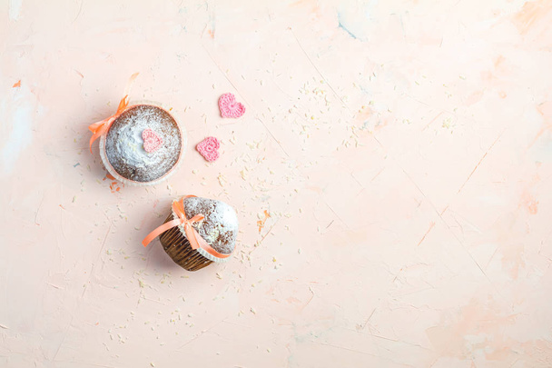 Lekkere zelfgemaakte heerlijke muffin op lichtroze koraal steen betonnen oppervlak met het breien van harten, bovenaanzicht, kopie ruimte wonen. Zoet voedsel voor valentines dy. - Foto, afbeelding