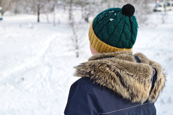 mluvit na telefonu boy v pletené čepici s kapucí bubo a kožešin na zimní procházce - Fotografie, Obrázek