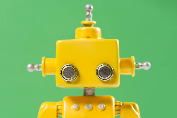 Portrait of a Cute, yellow, handmade robot on a green background. - Photo, image