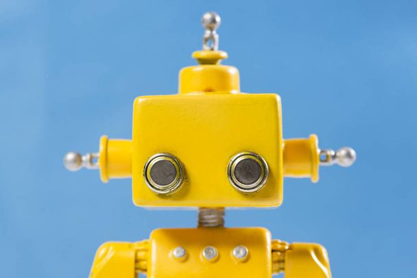 Portrait of a Cute, yellow, handmade robot on a blue background. - 写真・画像