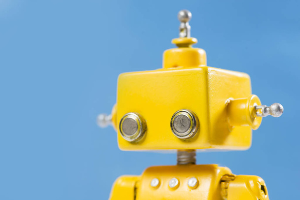 Portrait of a Cute, yellow, handmade robot on a blue background. - 写真・画像