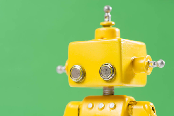 Portrait of a Cute, yellow, handmade robot on a green background. - Photo, image