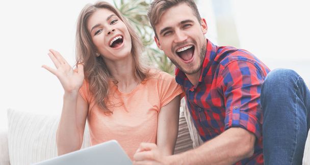 young couple rejoices,sitting on the couch in front of the open laptop - 写真・画像