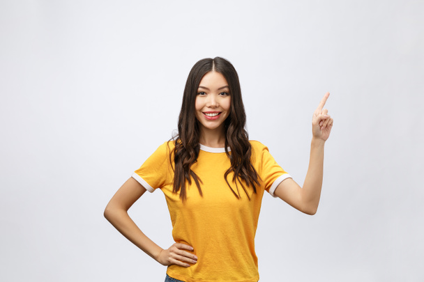 Portret van gelukkige jonge Aziatische vrouw met vinger wijzen omhoog - Foto, afbeelding