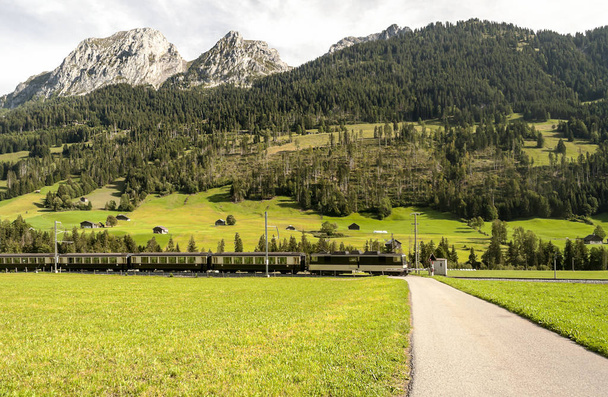 Βουνά των Άλπεων στο ελβετικό με ξύλινες καλύβες και λιβάδια σε μια ηλιόλουστη ημέρα. - Φωτογραφία, εικόνα