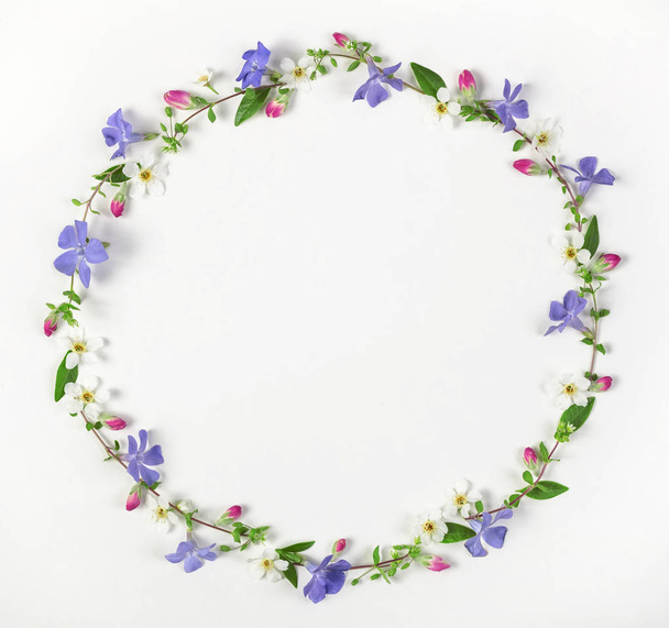 Round frame wreath made of spring wildflowers, lilac flowers, pink buds and leaves isolated on white background. Top view. Flat lay. - Fotografie, Obrázek