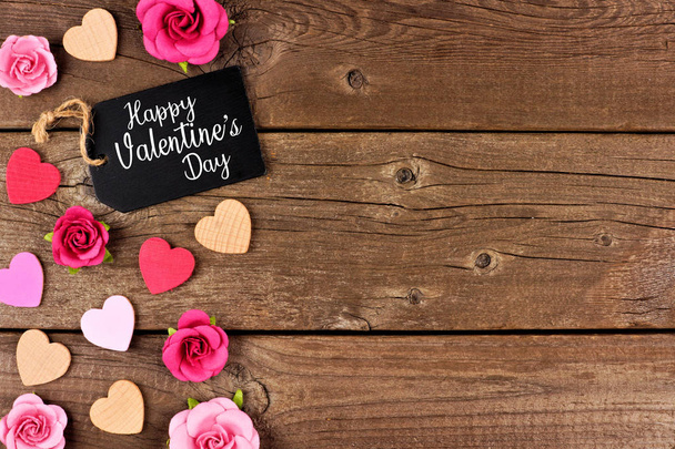 Buon San Valentino bordo laterale con tag regalo, cuori di legno e rose di carta su uno sfondo di legno rustico. Copia spazio
. - Foto, immagini