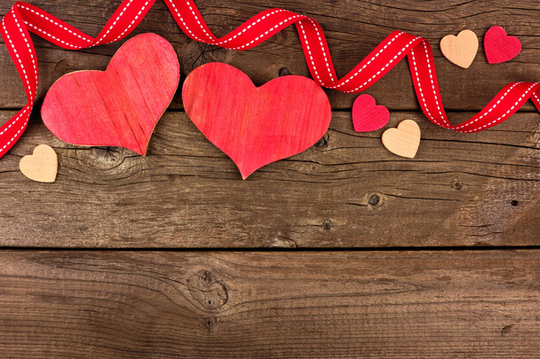 Valentines Day border of wood hearts and ribbon against a rustic wood background. Copy space. - Photo, Image