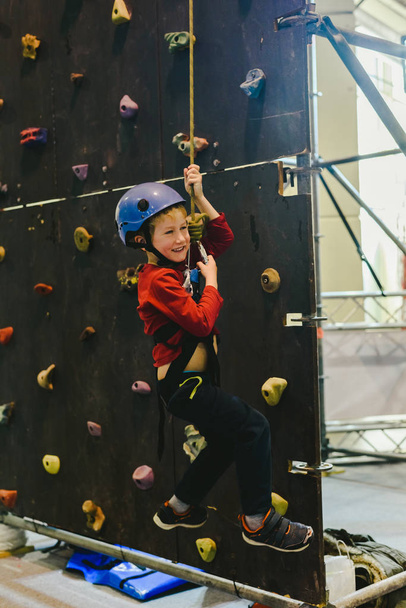 Child on the walls of a climbing wall with the help of a safety rope - Foto, Imagen