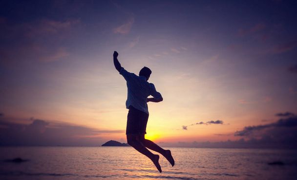 Silhouette d'un homme sautant au bord de la mer au coucher du soleil, concept homme et nature, style de vie beauté liberté vacances voyage
 - Photo, image