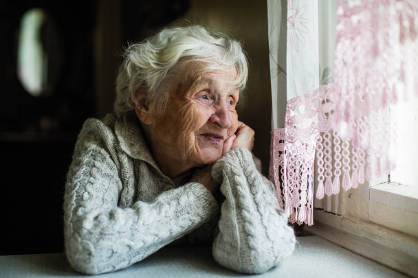 Femme âgée aux cheveux gris regarde par la fenêtre
. - Photo, image