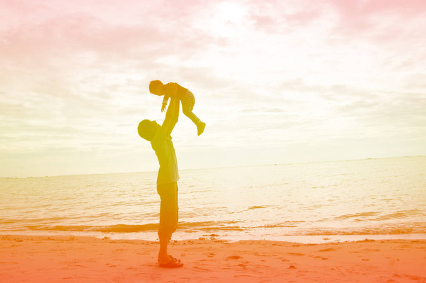 Padre e hijo jugando en la playa al atardecer. Concepto de familia amigable
. - Foto, Imagen