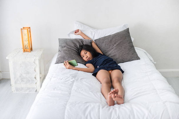 Felice ragazza asiatica utilizzando tablet sul letto a casa
 - Foto, immagini