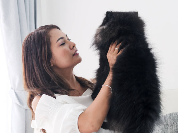 Happy Asian woman playing with her black dog on sofa at home, lifestyle concept - Fotoğraf, Görsel