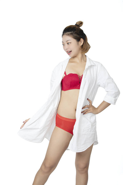 Mooie Chinese vrouw poseren in een wit overhemd en een paar rode slipje en BH geïsoleerd op een witte achtergrond. - Foto, afbeelding