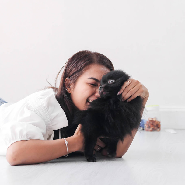 Happy Asian woman lying on floor and touching her black dog with window light, lifestyle concept. - Foto, Imagem