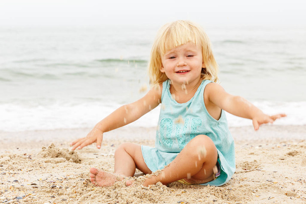 A little girl with blond hair playing on the beach. Copy space. - Photo, Image
