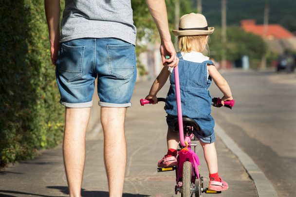 Father is teaching his daughter to ride a bicycle. - Foto, immagini