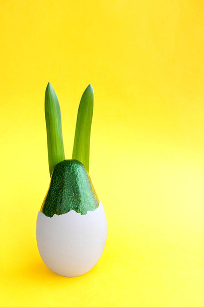 Bela ideia de fundo decoração criativa com fresco coelho abacate verde eclodindo de um ovo em papel amarelo brilhante. Conceito de cartão.Férias decorativas theme.Closeup.Vista frontal. Espaço de cópia
 - Foto, Imagem