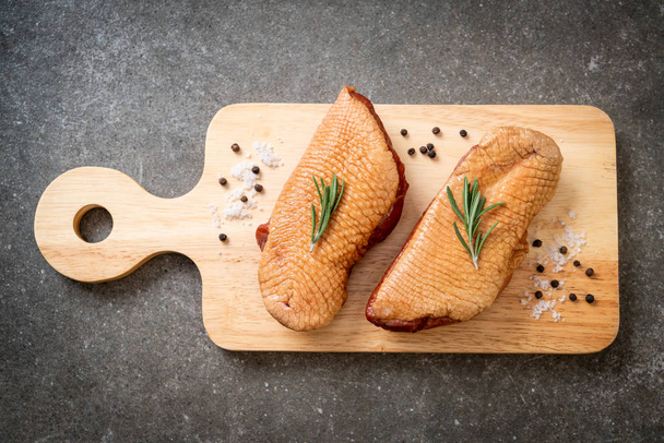 pechuga fresca de pato crudo sobre tabla de madera con ingredientes
 - Foto, Imagen