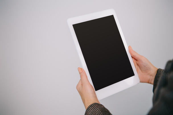 cropped view on businesswoman using digital tablet with blank screen isolated on grey - Foto, afbeelding