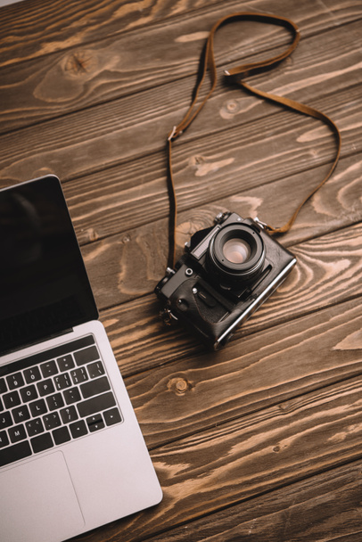 laptop και ρετρό φωτογραφία κάμερα στο ξύλινο τραπέζι - Φωτογραφία, εικόνα