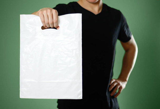 A man holding a white plastic bag. Close up. Isolated on green background. - Photo, image