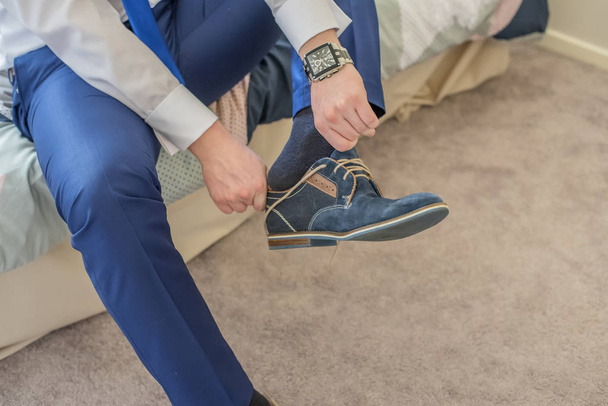 Άνθρωπος με καρπό ρολόι βάζοντας σε hes μπλε παπούτσια. - Φωτογραφία, εικόνα