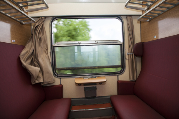 Zugabteil mit roten Sitzen und Blick aus dem Fenster - Foto, Bild