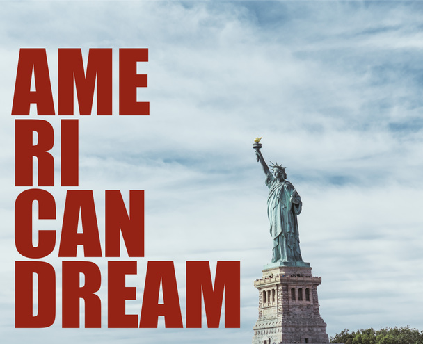 STATUE OF LIBERTY, NEW YORK, USA - OCTOBER 8, 2018: statue of liberty in new york against blue cloudy sky background with "american dream" red lettering, usa - Zdjęcie, obraz