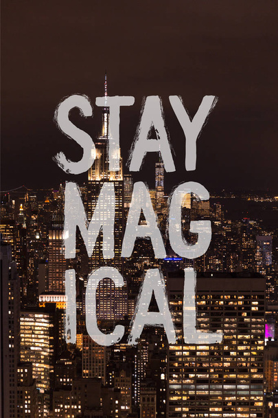 Luftaufnahme von Gebäuden und nächtlichen Stadtlichtern mit "stay magical" -Schriftzug in New York, USA - Foto, Bild