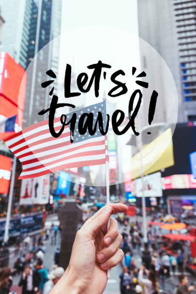 partial view of man holding american flag on new york city street with "lets travel" lettering in circle - Photo, Image