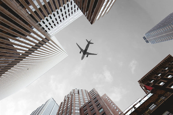 vista inferior de rascacielos y avión en el cielo nublado en la ciudad de Nueva York, EE.UU.
 - Foto, Imagen