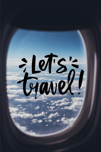 view of blue cloudy sky from airplane with "lets travel" lettering on window - Фото, зображення