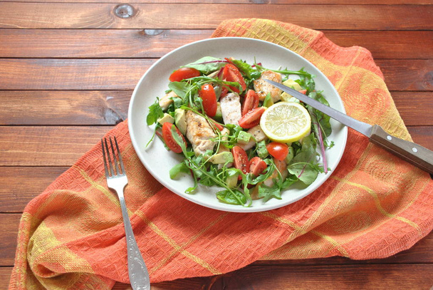 Chicken salad with avocado and cherry tomatoes, arugula and beet leaves. Healthy lunch bowl with vegetables and chicken on a wooden background. Healthy food concept - Foto, Imagem