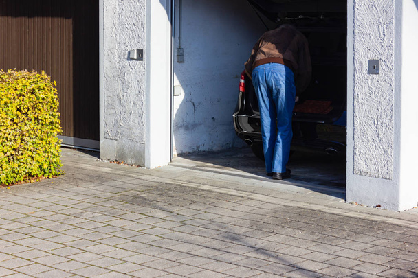 Senior man voor zijn garage in Zuid-Duitsland-Beieren herfst middag - Foto, afbeelding