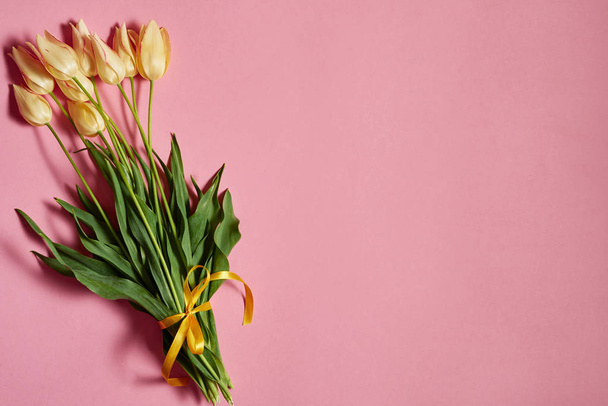 Bouquet of yellow tulips on pink pastel background, copy space. Spring minimal concept. Womens Day, Mothers Day, Valentine's Day, Easter, birthday. Nature background. Flat lay, top view - Photo, image