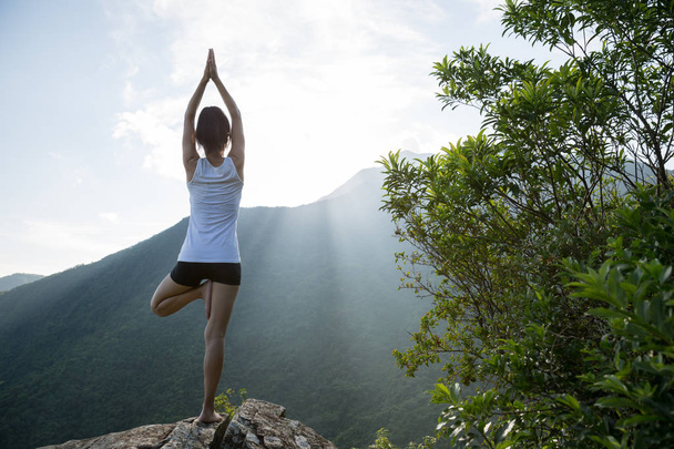 Yoga woman meditating on mountain peak cliff edge in sunrise - Fotografie, Obrázek