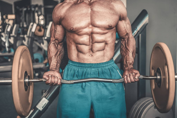 Brutal strong bodybuilder athletic aged man pumping up muscles workout bodybuilding concept background - muscular bodybuilder handsome men doing exercises in gym naked torso sport and diet concept - Photo, image